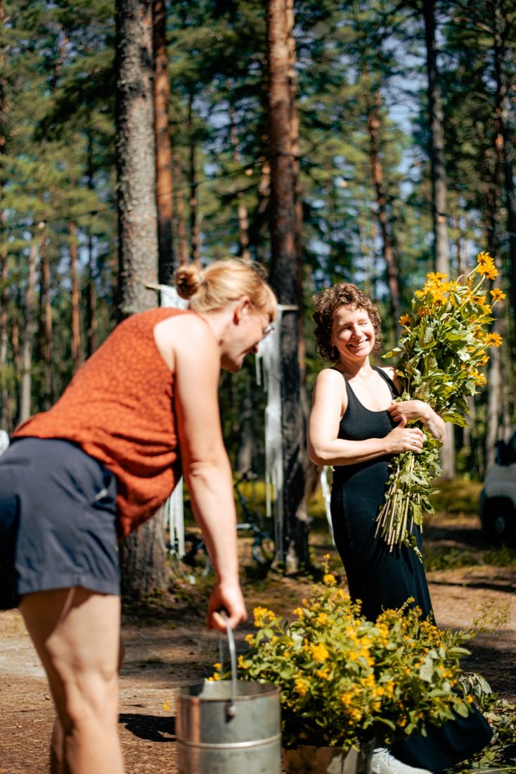 Kaks naist seavad metsateel põldlilli ämbrisse